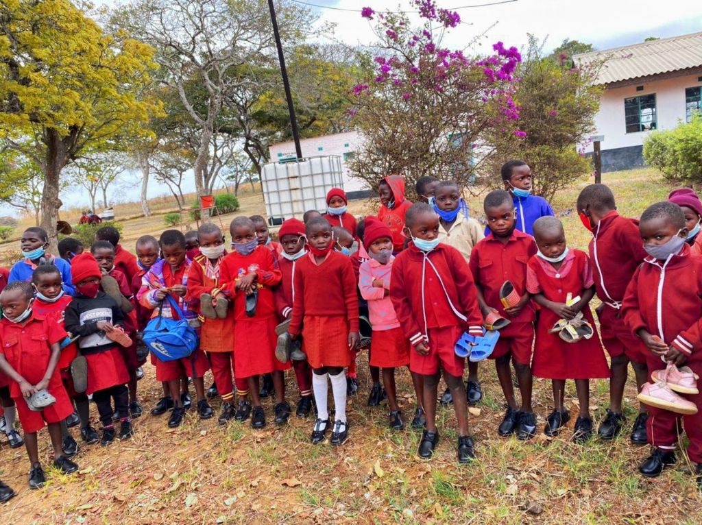 Children standing outdoors in red school uniforms